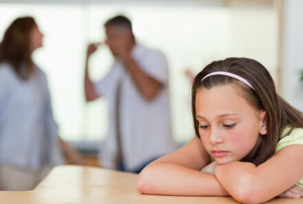 sad girl with parents fighting in background
