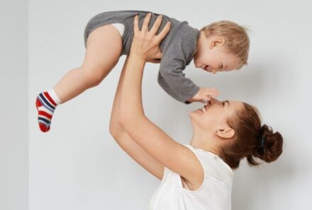 mom playfully holding baby in air